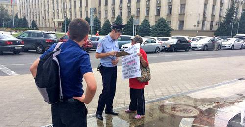 Сотрудник полиции общается с участницей одиночного пикета дольщиков ЖК "Анит-сити". Краснодар, 7 августа 2017 г. Фото Светланы Кравченко для "Кавказского узла"